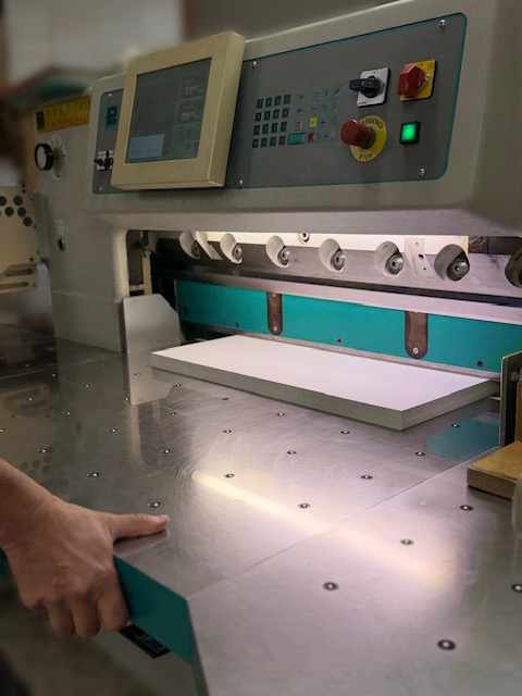 Découpe de feuilles au massicot dans l'atelier de L'Imprim à Apt