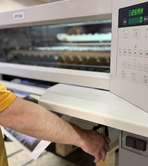Conducteur récupérant une feuille fraichement imprimée à la sortie de la presse offset de L'Imprim à Apt. La feuille est déjà sèche grâce à la LED UV